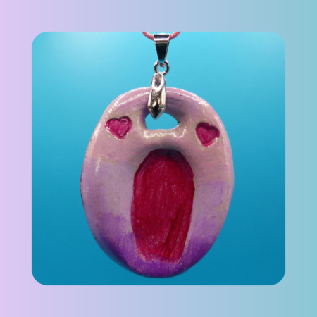 Vue de face du pendentif Petit Lien en argile autodurcissante, pièce unique, fait main, couleur rose clair et foncé, motif coeur, forme organique allongée, surface douce et brillante. Posé sur fond bleu.