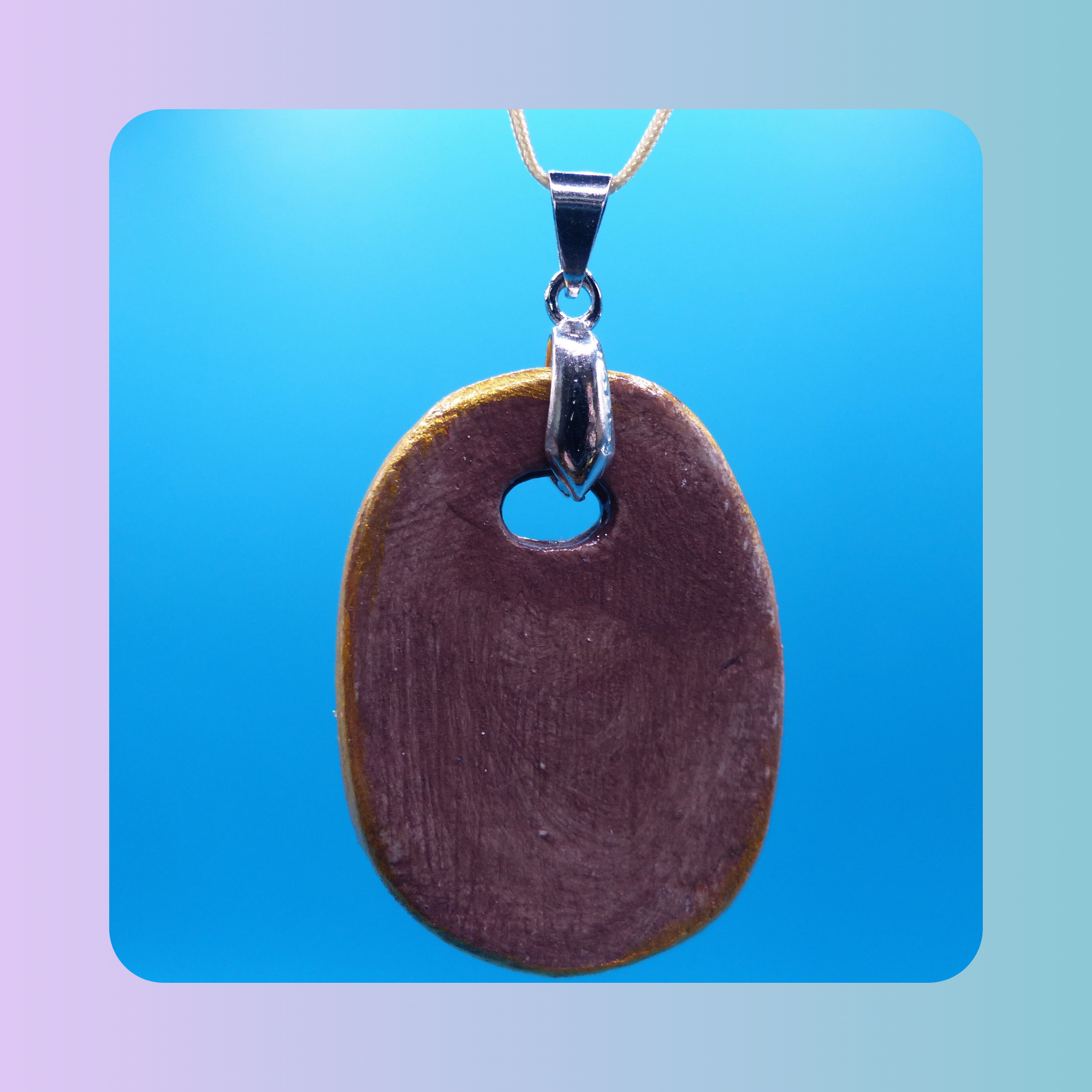 Dos du pendentif Petit Lien en argile autodurcissante, posé sur fond bleu. Vue sur l’attache qui accueille le cordon.